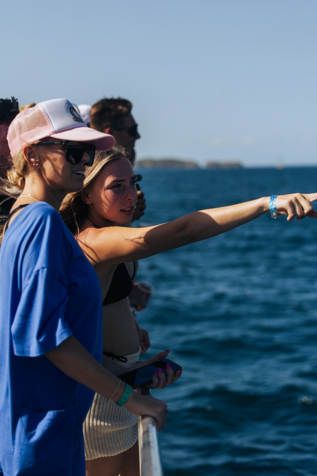 Travelers at a boat rail, one pointing out across the water