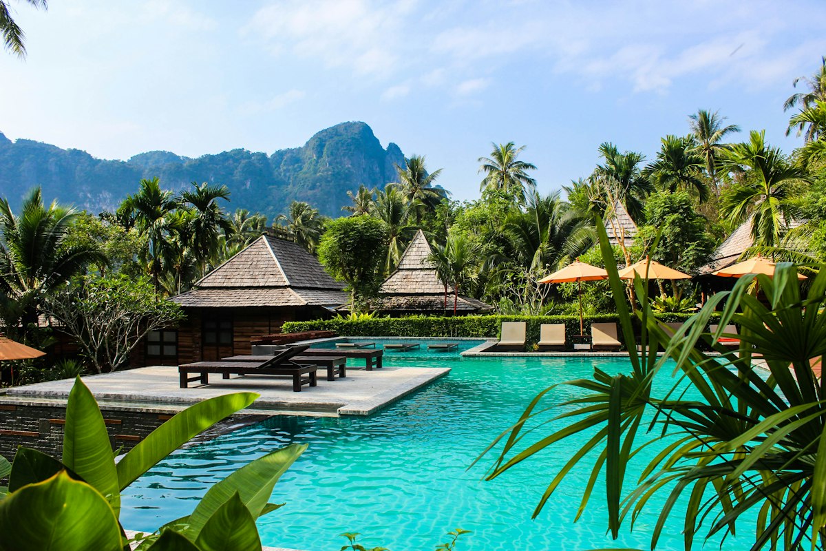 Poolside villas surrounded by palm trees and limestone cliffs