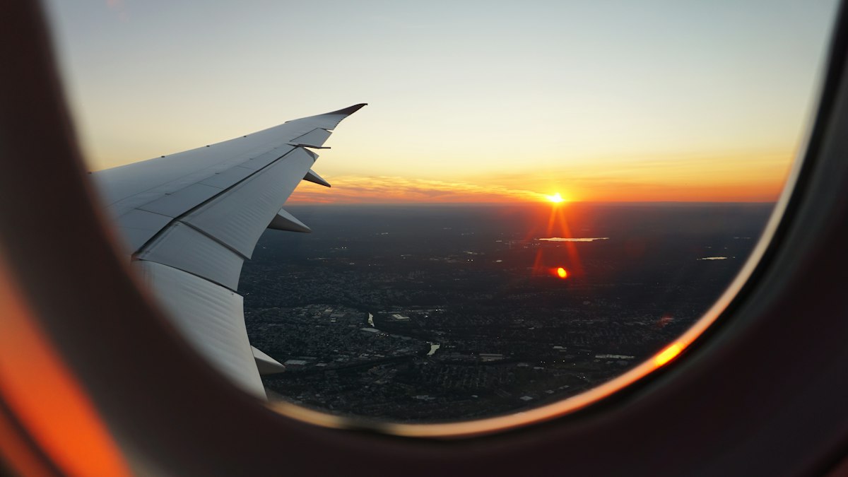 View through an airplane window of the sun setting over a city