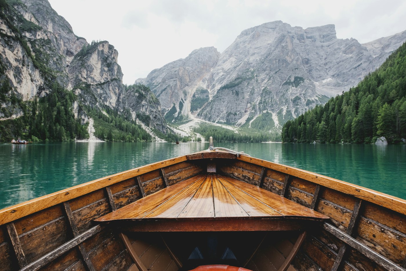 The bow of a wooden boat gliding across a mountain lake